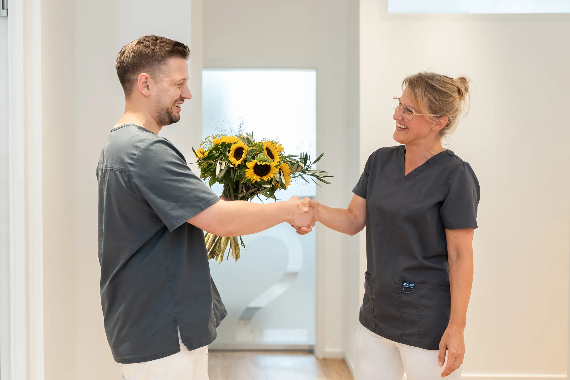 Teammitglied überreicht Kollegin einen Blumenstrauß