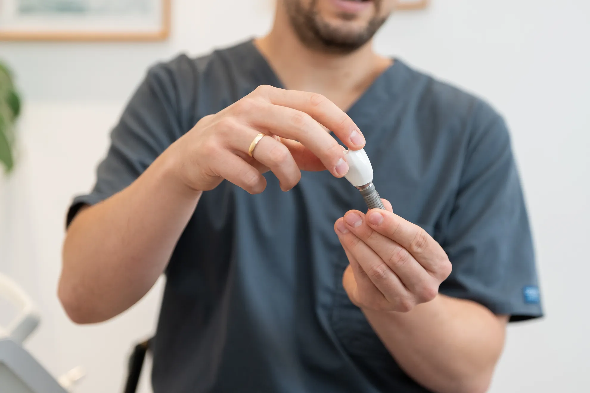 Zahnarzt hält Modell Implantat in der Hand